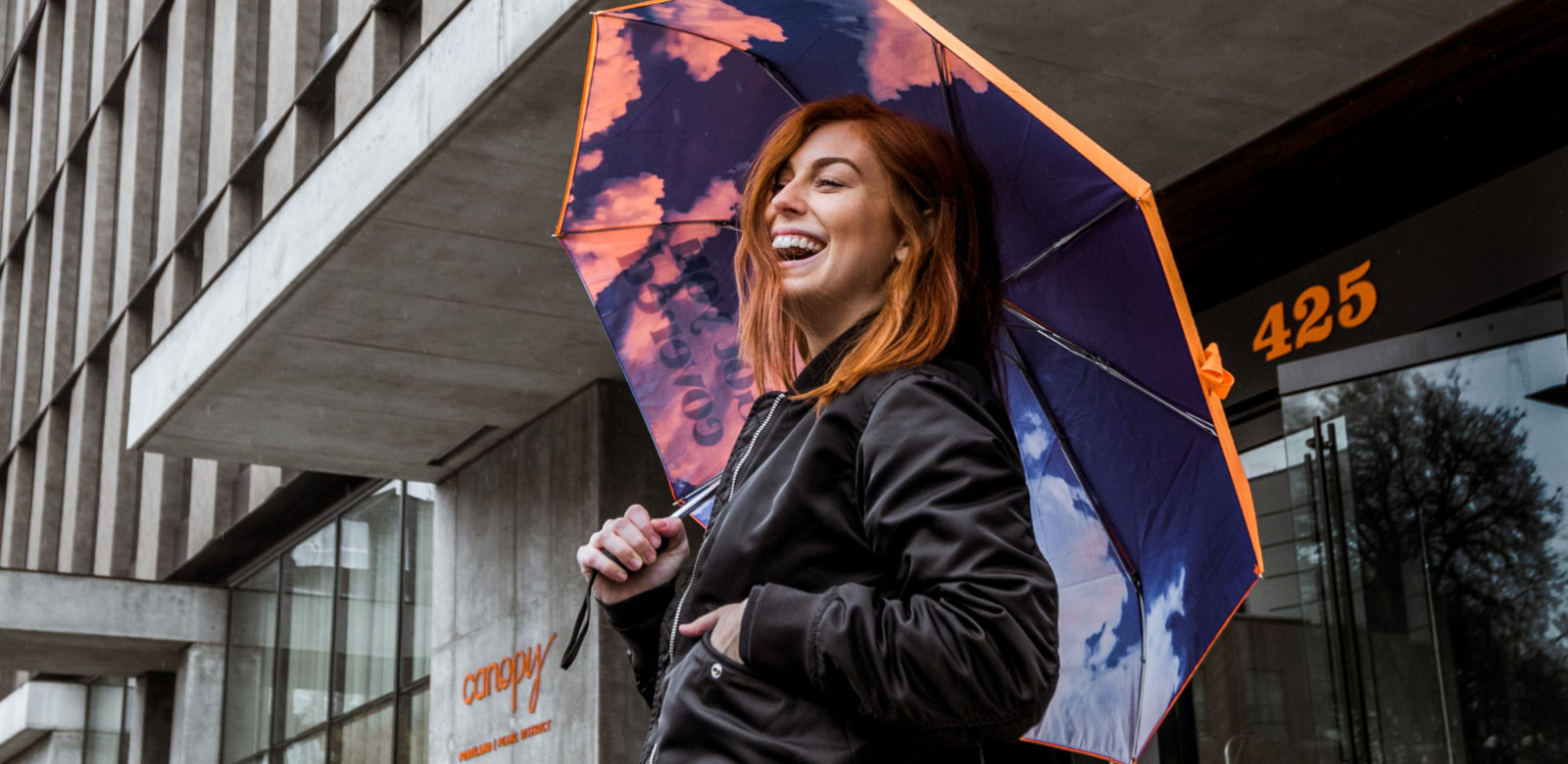 Woman holding Canopy branded umbrella outside hotel at Canopy Portland | Pearl District