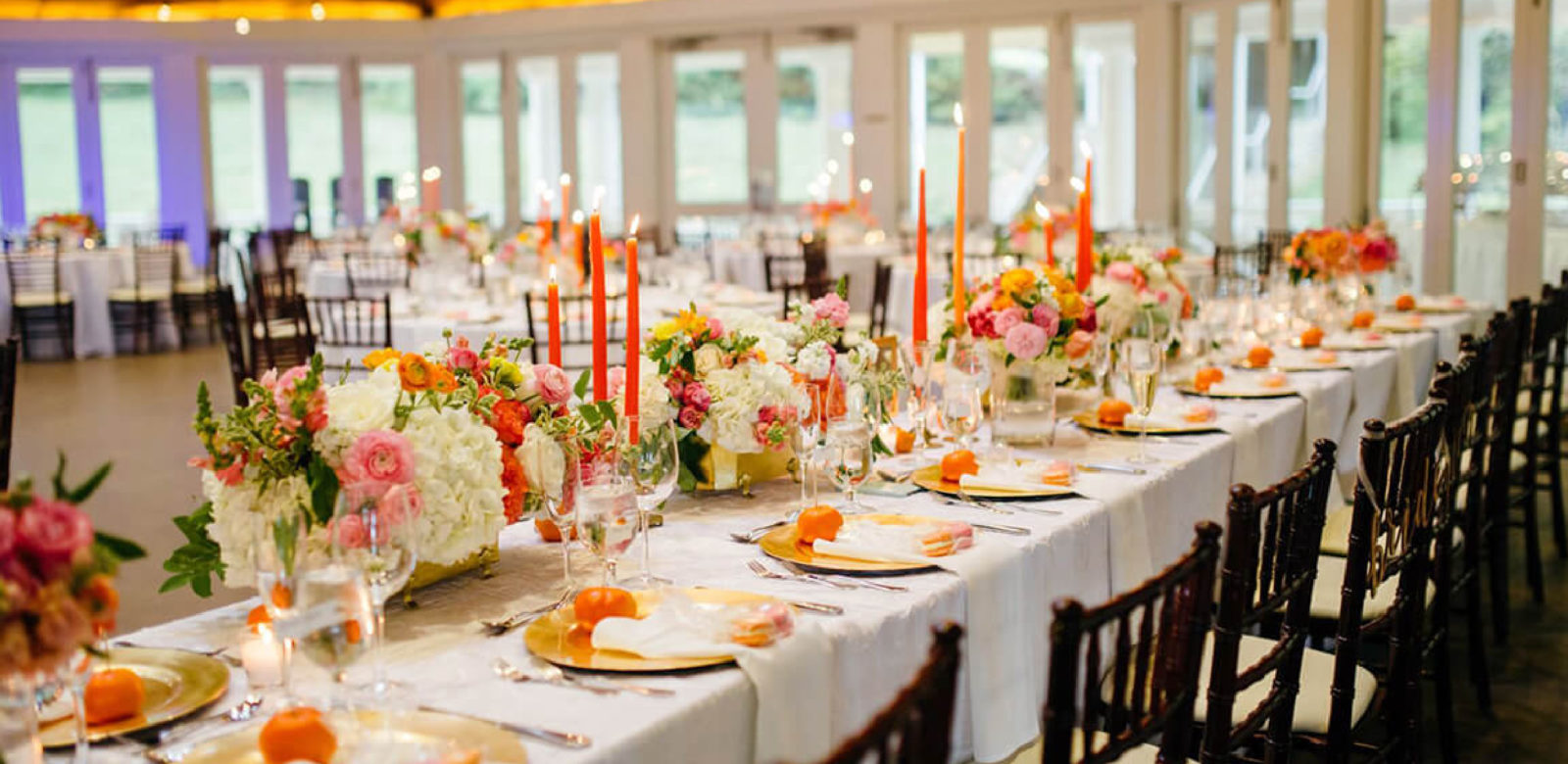 Table setting for a wedding with orange accents at Airlie